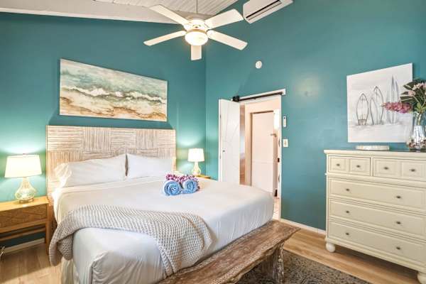 Rest easy in your serene primary bedroom featuring a luxurious king bed, vaulted ceiling, and soothing coastal-inspired blue accent walls.