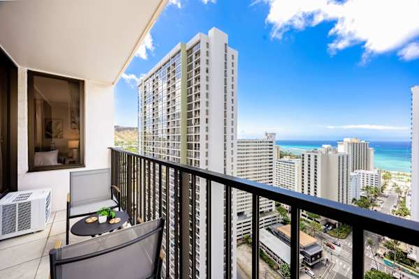 Your private balcony features outdoor seating with a patio set and sweeping views of surrounding high-rises and the ocean.
