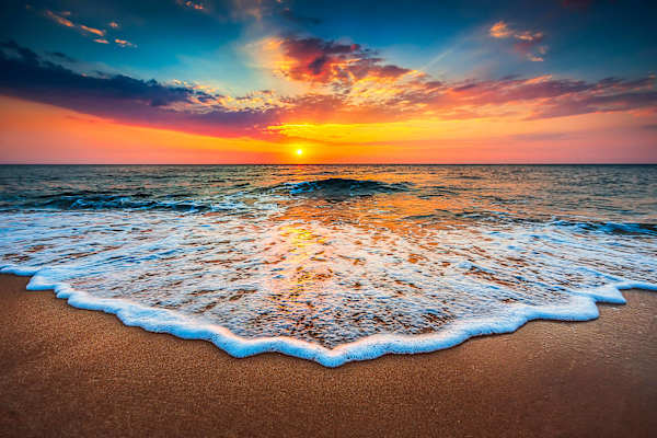 Golden Sunset Over Ocean Waves Wading Along the Sandy Beach