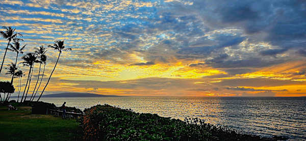 End your day with a breathtaking, golden Kamaole Beach sunset framed by towering palm trees and a dramatic, colorful sky, an iconic Hawaiian moment you can experience just steps from your property.