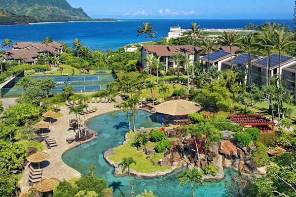 Aerial resort pools wind through lush gardens beside ocean waters