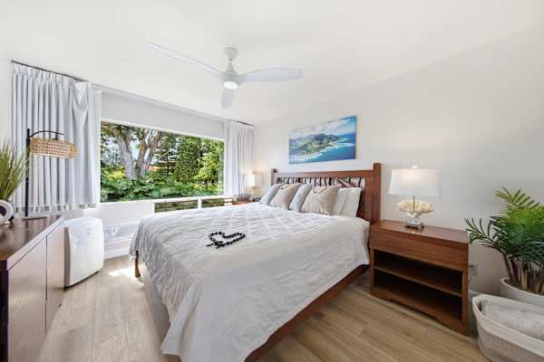 Restful bedroom features layered bedding, calming artwork, and natural brightness