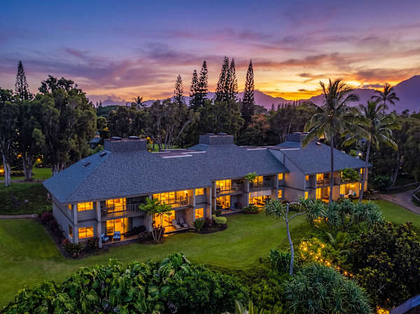 Evening property view glows warmly against mountains, gardens, and ocean