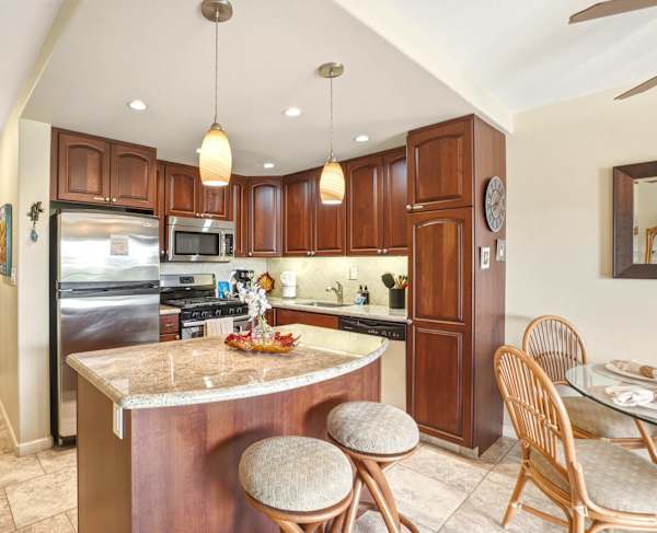 Enjoy quick bites and morning coffee at your convenient kitchen island with granite countertops, bar seating, and warm pendant lighting.