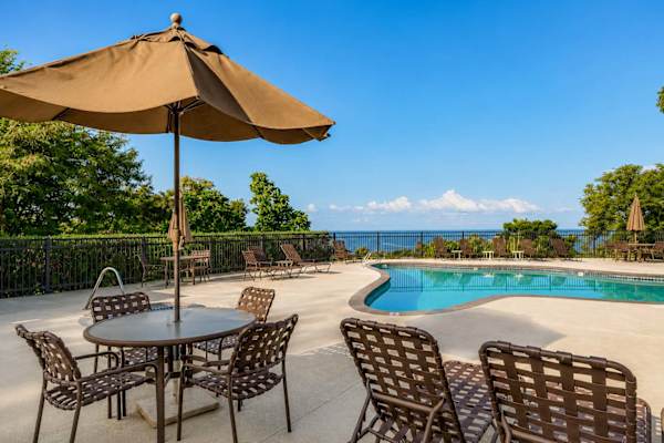 Poolside deck with umbrella table, lounge chairs, and ocean views