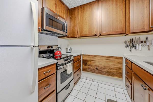 Kitchen layout with full-size refrigerator, microwave, stove & wood cabinets