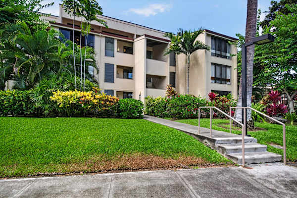 Condo building exterior with paved walkways and lush greenery
