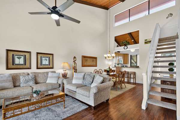 Living area featuring comfortable seating, high ceilings, and stairs to loft