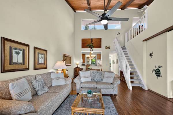 Spacious living room with high ceilings, ceiling fan, and loft access