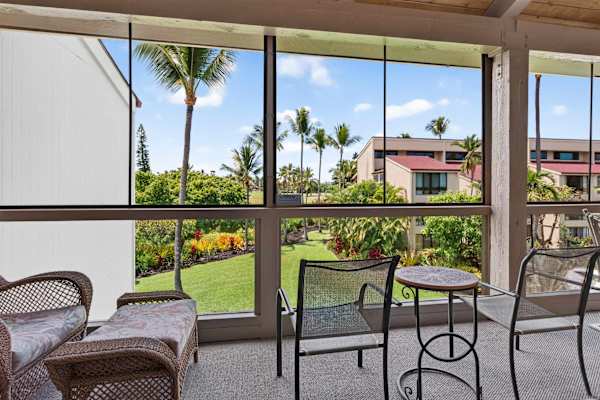 Screened balcony with comfortable seating and garden views