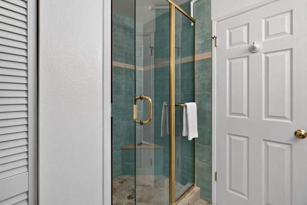 Walk-in glass shower enclosure with blue-green tile wall
