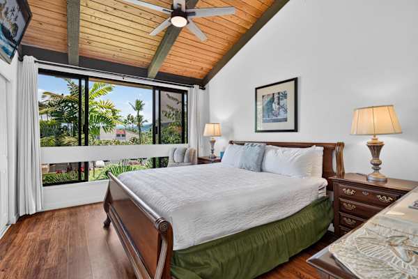 Primary bedroom featuring king bed, vaulted wood ceiling, and large window