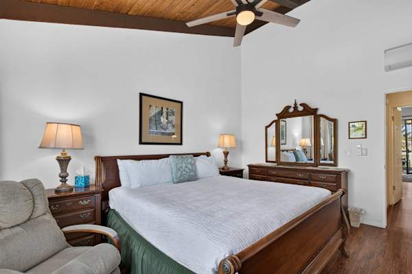 Primary bedroom featuring king bed, wooden vanity dresser, and ceiling fan