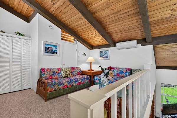Upstairs loft featuring twin beds, vaulted wood ceilings, and closet space