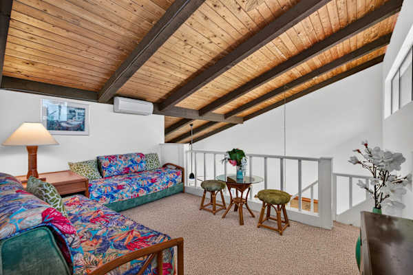 Upstairs loft bedroom with twin beds, small seating area, and vaulted ceiling