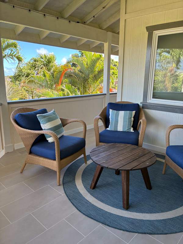 Covered outdoor lounge nook featuring woven chairs & Accent table