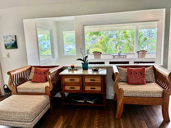 Sunlit living room seating area with natural wood chairs and poufs