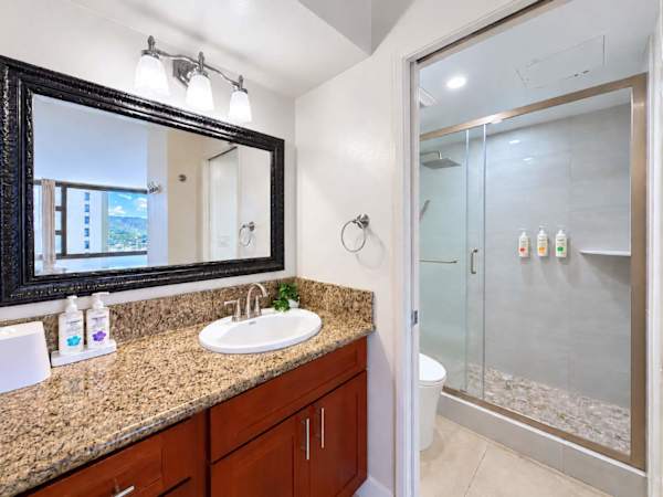 Freshen up conveniently in this spacious sink area featuring a wide mirror and bright vanity lights.