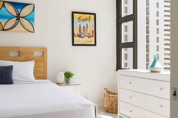 Embrace serene coastal charm in this bright, island-inspired bedroom accented with vibrant surf art and natural light.