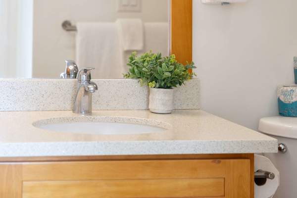 Refresh in a clean, modern bathroom vanity featuring smooth stone countertops, warm wood cabinetry, and sleek chrome fixtures.
