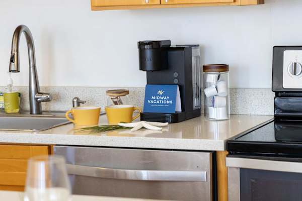 Brew your morning cup of coffee with ease at this fully appointed kitchen station, complete with a Keurig coffee maker, mugs, and modern stainless steel appliances.