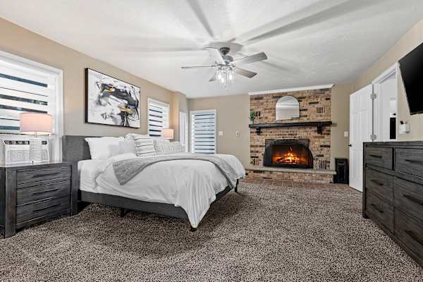 Rest easy in the grandeur of Bedroom #1's king-sized bed, with the serene charm of a non-operational fireplace adding a cozy aesthetic to your peaceful retreat.