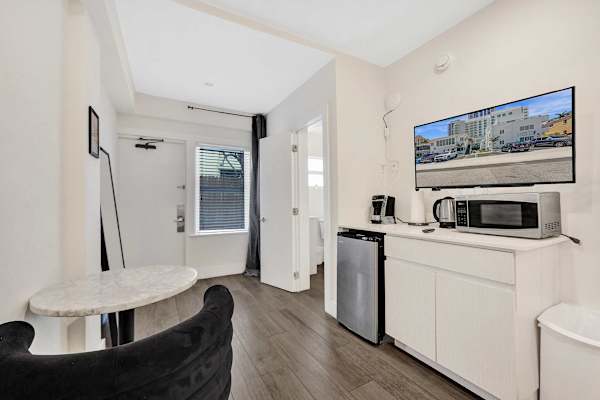 Bright studio kitchenette with mini-fridge and TV