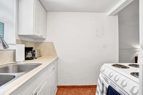 Kitchen with cabinets, sink and stove overview