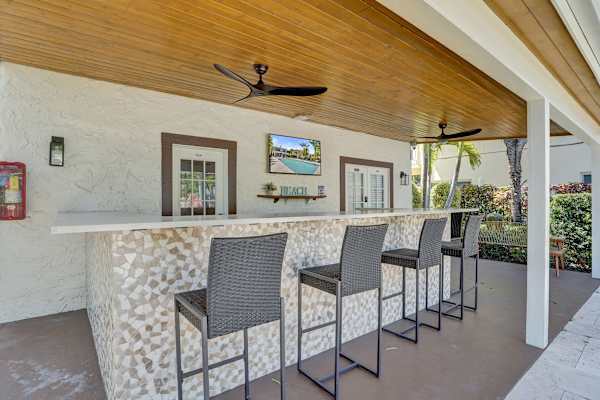 Covered outdoor bar with TV and wicker stools