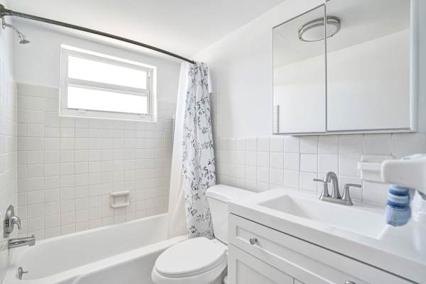 Clean white bathroom with tub-shower and vanity