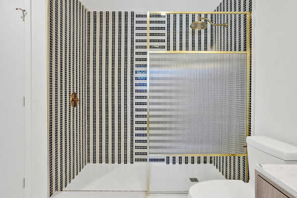 Designer tiled shower with gold-framed glass enclosure