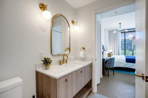 Bathroom vanity with gold fixtures and oval mirror
