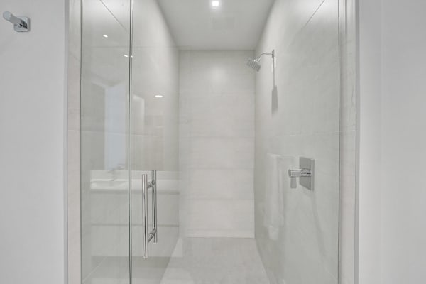 Walk-in glass shower with marble tiles