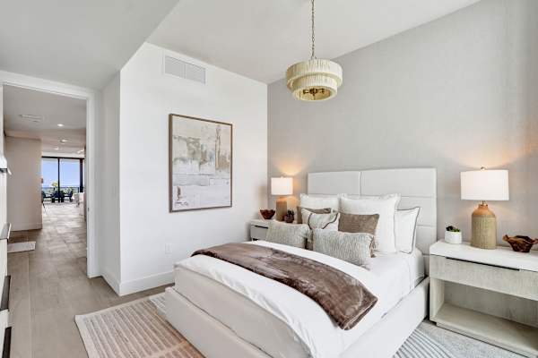 Bright bedroom with queen bed and ocean view beyond
