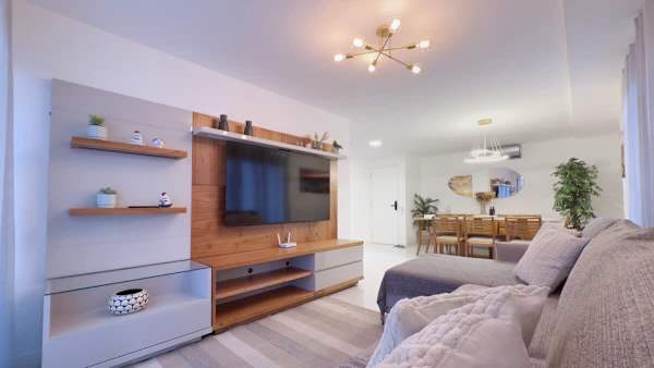Sala espaçosa com TV Smart, sofá confortável e integração com a mesa de jantar para até 8 pessoas.