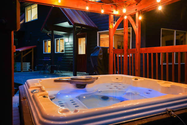 Enjoy a covered hot tub and soak in the beauty of the trees surrounding the home. 