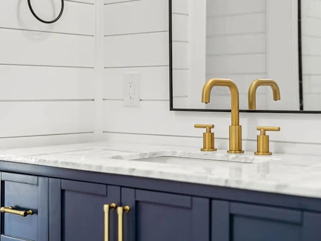 Elegant bathroom vanity with marble-style countertop and brushed brass fixtures.