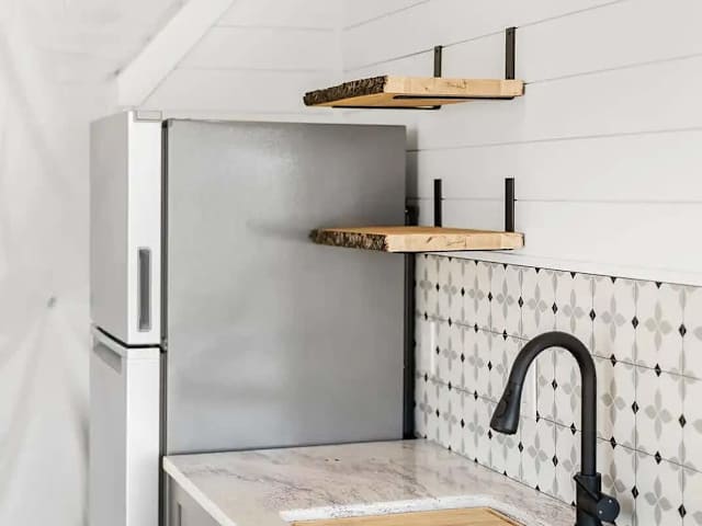 Functional kitchenette with sink, shelving, and fridge to keep essentials handy during your getaway.