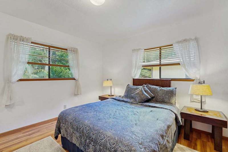 Cozy  Bedroom Featuring Double Windows and Wooden Nightstands