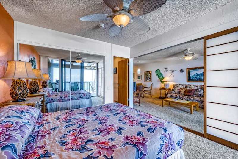 Comfortable bedroom setup featuring a cozy bed, ceiling fan, and full-length mirrored closets