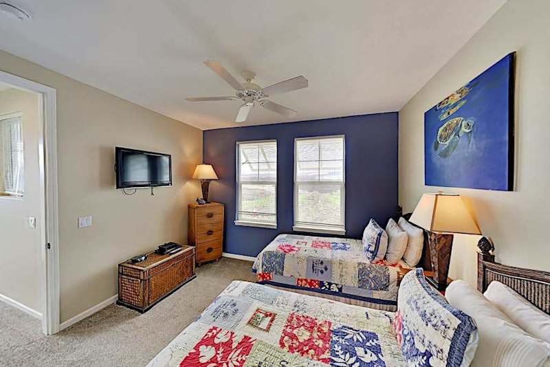 Guest bedroom with two twin beds, flat screen tv and an en-suite bathroom.