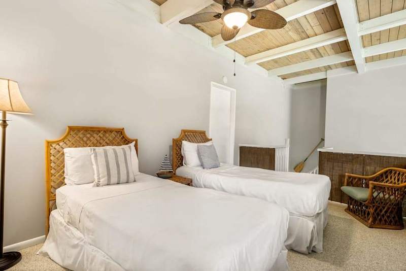 A welcoming twin bedroom layout featuring comfortable beds with woven headboards and a warm standing lamp