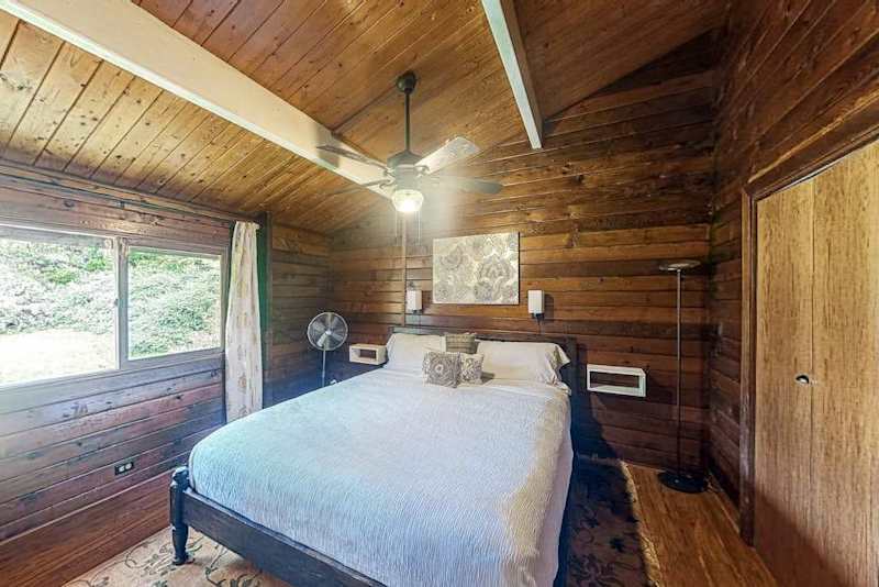 Guest bedroom with a queen bed, ceiling fan and lots of natural light.