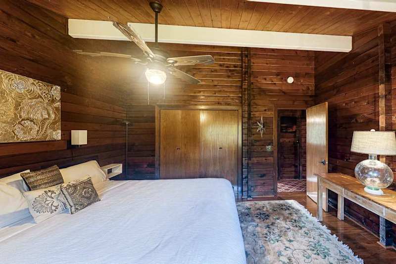 Guest bedroom with a queen bed, ceiling fan and lots of natural light.