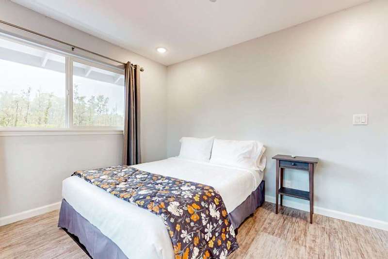 Guest room with queen bed and large picture windows.