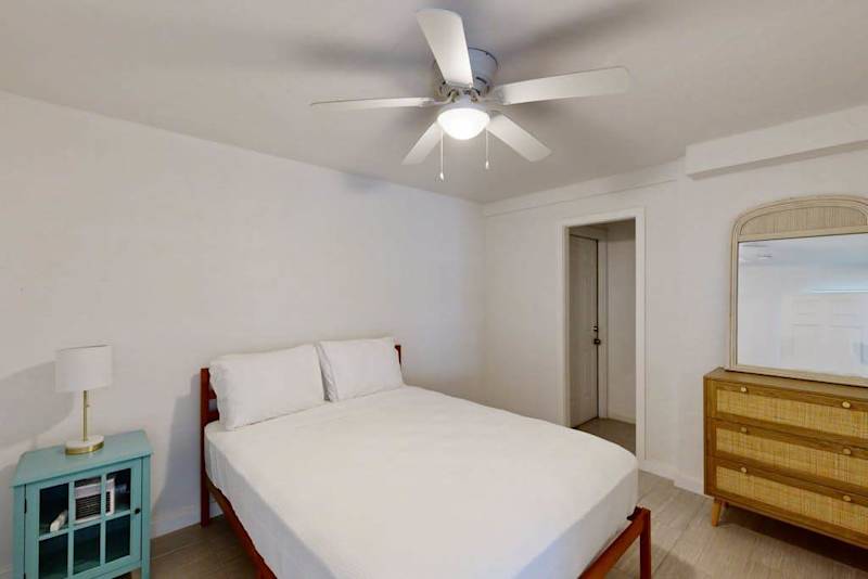 Second bedroom includes queen bed ceiling fan dresser and light