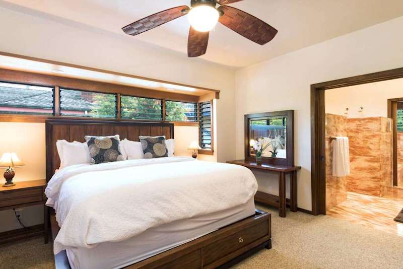 Cozy bedroom presents a comfortable bed, ceiling fan, and windows