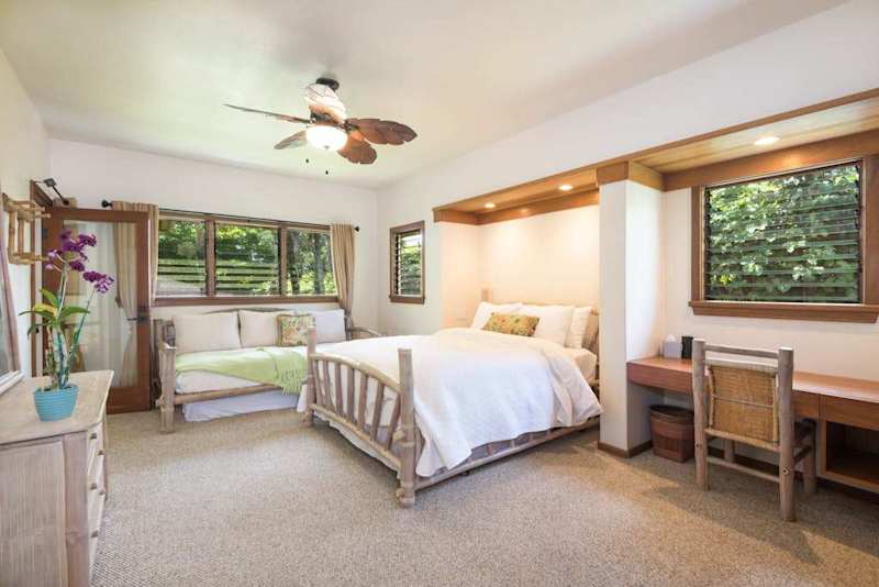 Bright bedroom offers comfortable bedding, practical furnishings, and garden views
