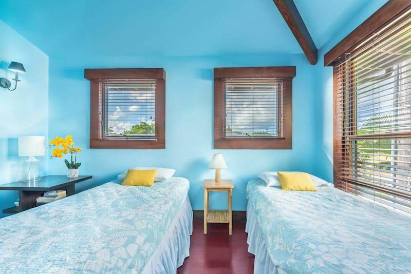 Modern bedroom features twin beds, fresh linens, and garden views