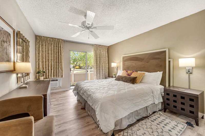 Primary Bedroom Featuring King Bed, Dresser, Ceiling Fan, and Sliding Patio Access